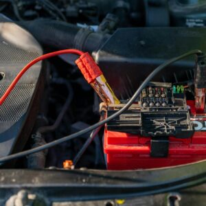 12V car battery with jumper cables connected under the hood